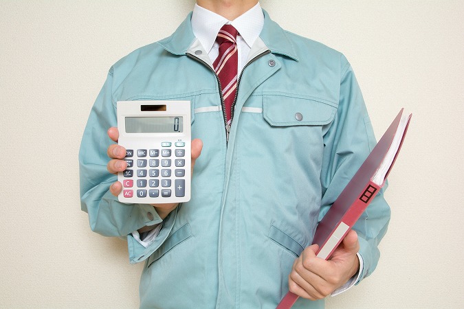 電卓見せる作業着男性